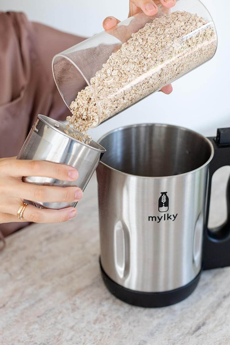 Versare l'avena nel filtro della macchina Mylky per preparare il latte vegetale